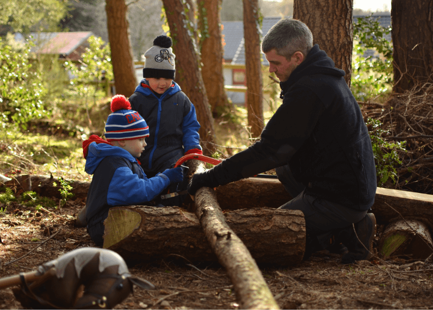Daniel Harrison teaching children how to saw wood at Nature Nurture