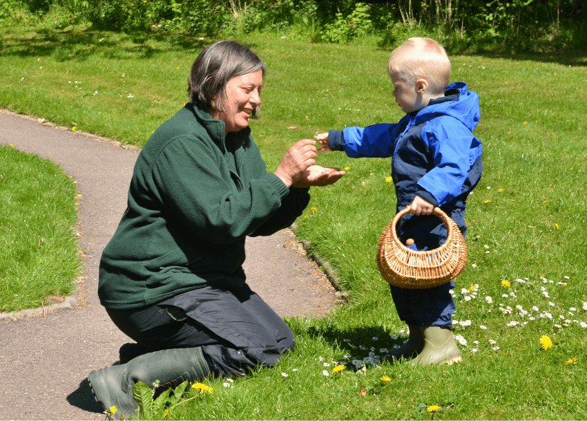 Terri Harrison picking flowers with a child at Nature Nurture