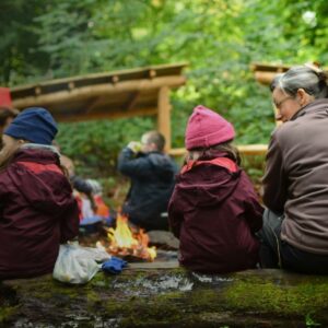 Children eating and drinking around the campfire at Nature Nurture