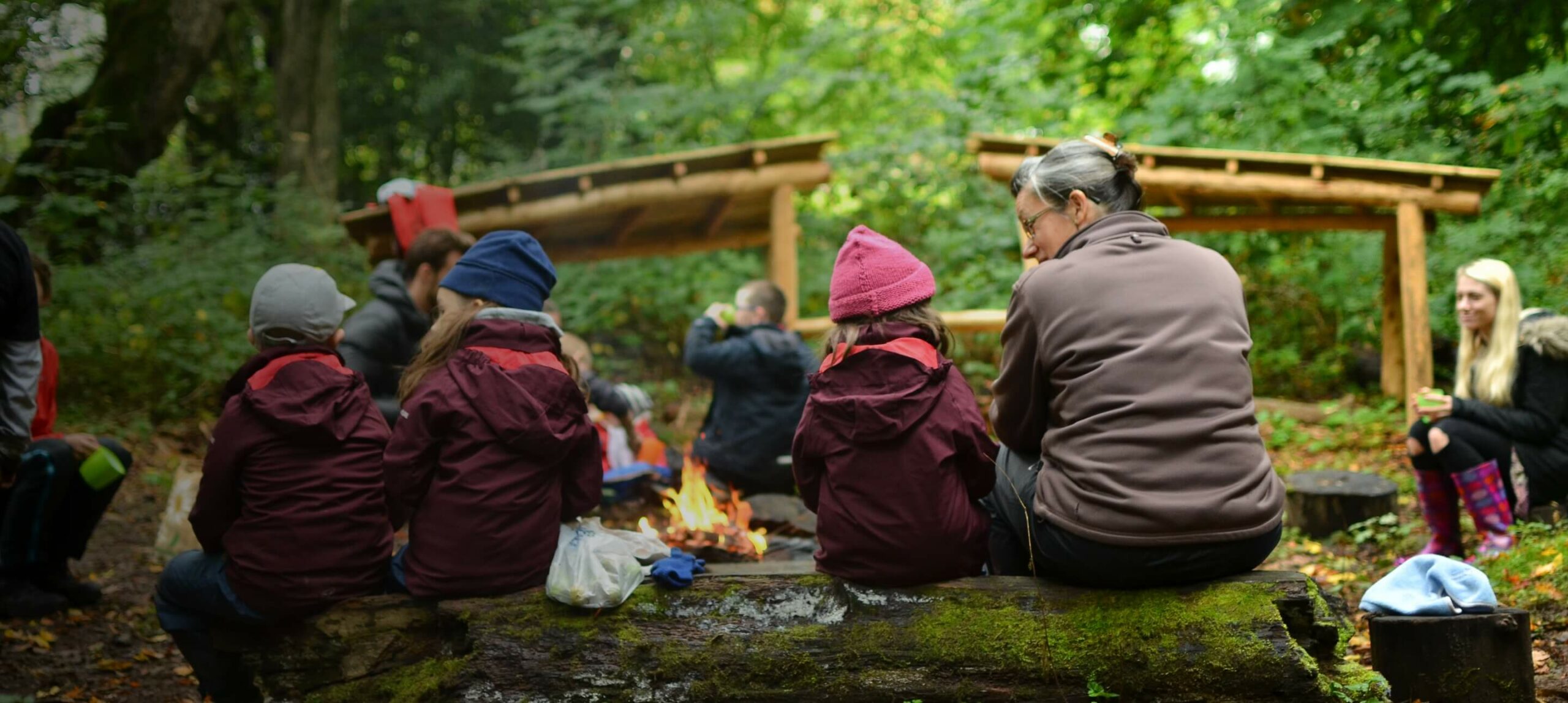 Children eating and drinking around the campfire at Nature Nurture