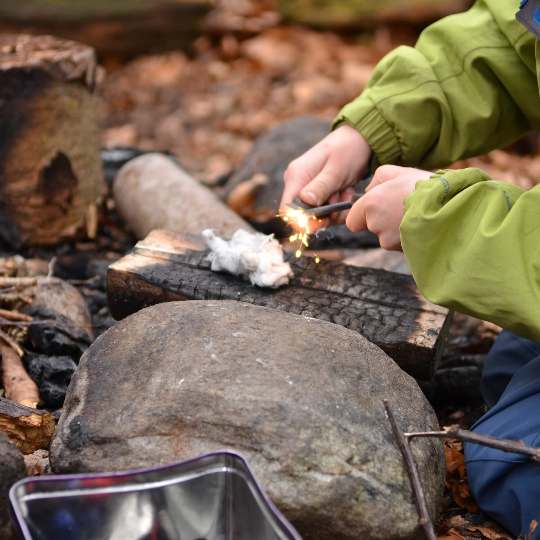 Child lighting a fire with a fire steel and cotton wool at Nature Nurture