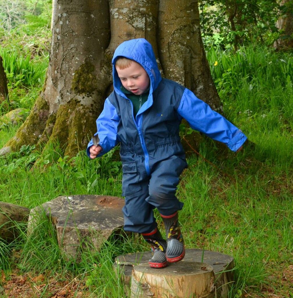 A child jumping from log to log in the woods