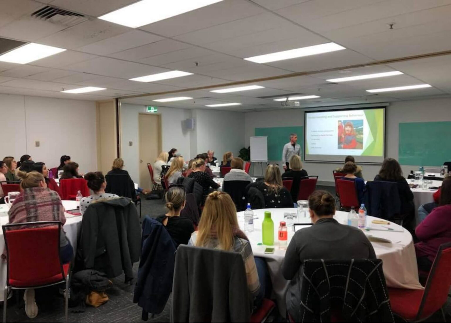 Training and Consultancy takes place in a large room with many people sat at tables