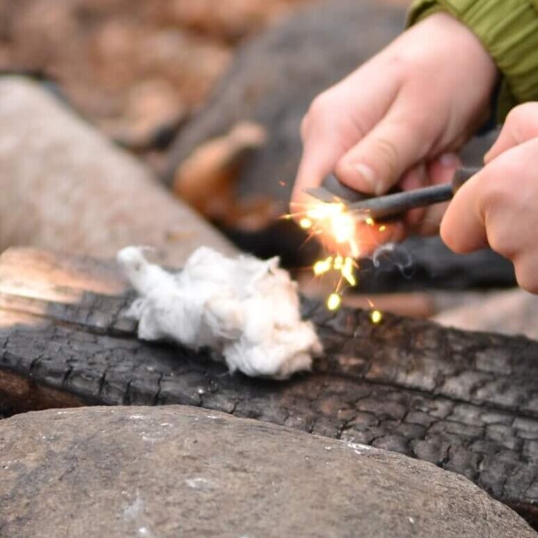 Child lighting a fire with a fire steel and cotton wool at Nature Nurture