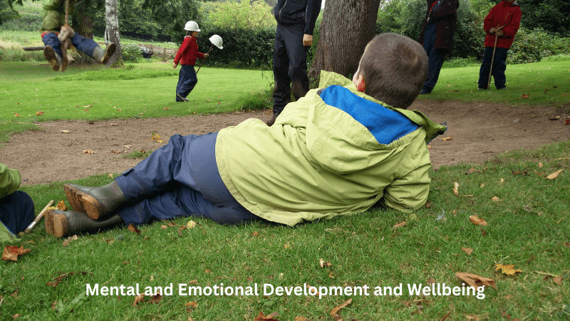 Mental and Emotional Wellbeing – boy relaxing on the grass watching others at play. 