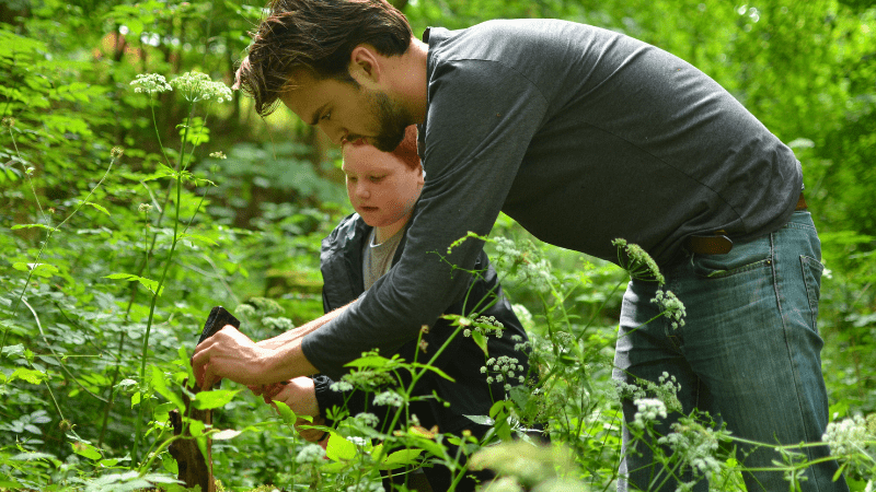 adult and child exploring an overgrown area