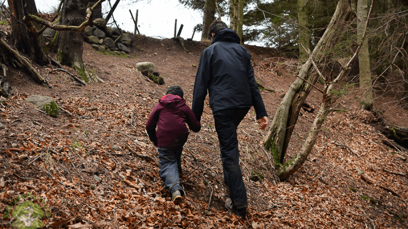 adult and child climbing a steep hill together