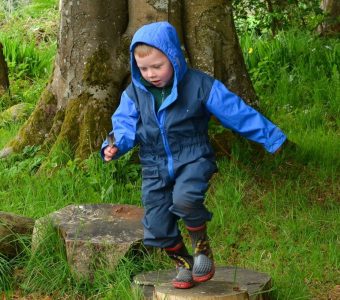 A child jumping from log to log in the woods