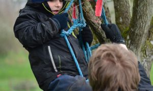 Child climbing a tree with rope at Nature Nurture